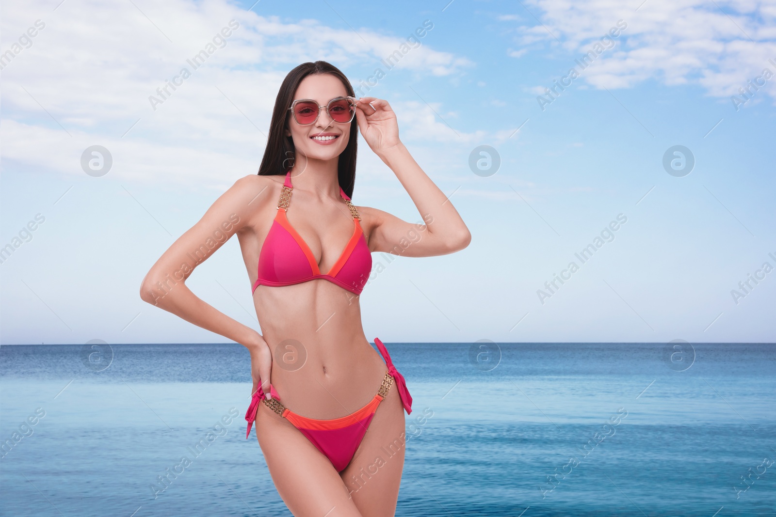 Image of Happy woman in stylish pink bikini and sunglasses near sea, space for text