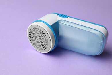 Photo of Modern fabric shaver for lint removing on purple background