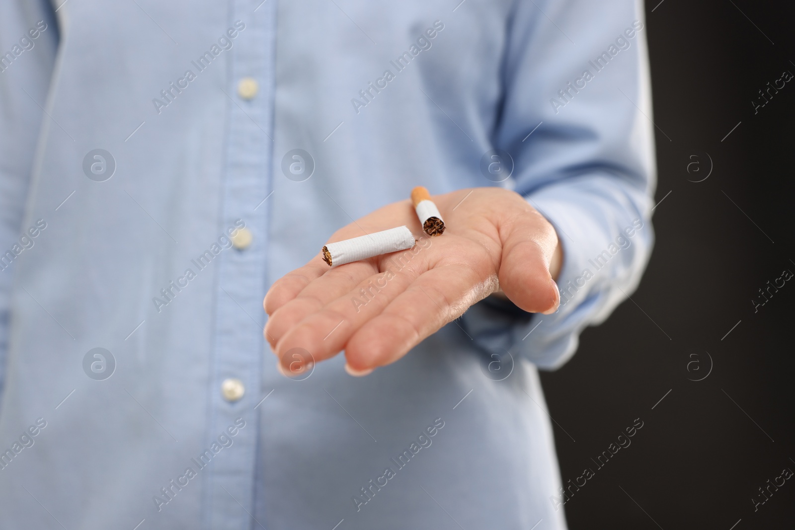 Photo of Stop smoking concept. Woman holding broken cigarette on black background, closeup