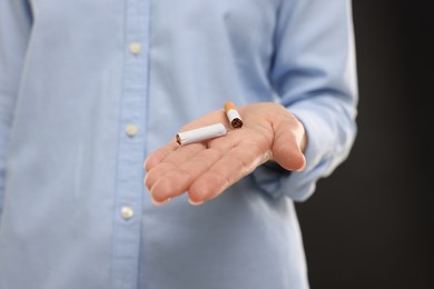 Photo of Stop smoking concept. Woman holding broken cigarette on black background, closeup