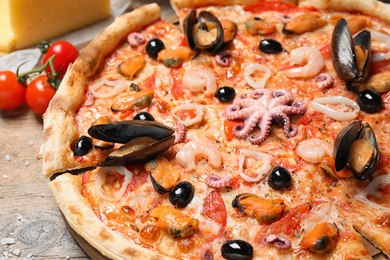 Photo of Tasty fresh pizza with seafood on table, closeup