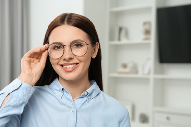 Portrait of smiling woman in stylish eyeglasses at home. Space for text