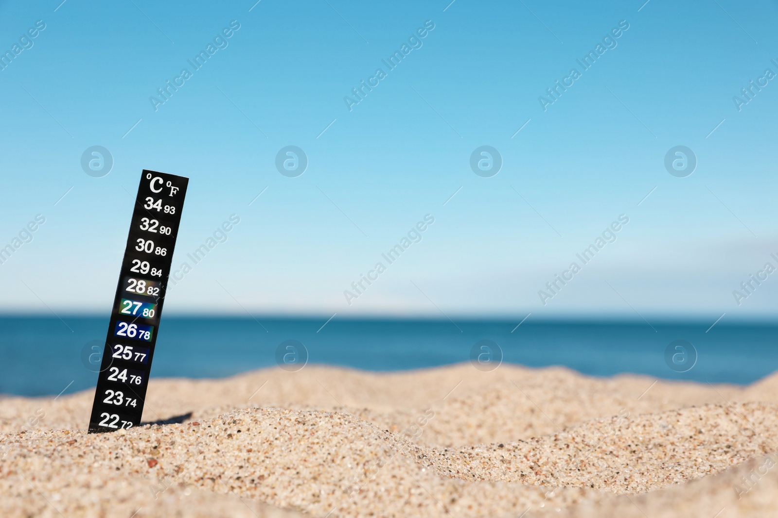 Photo of Weather thermometer in sand near sea, space for text