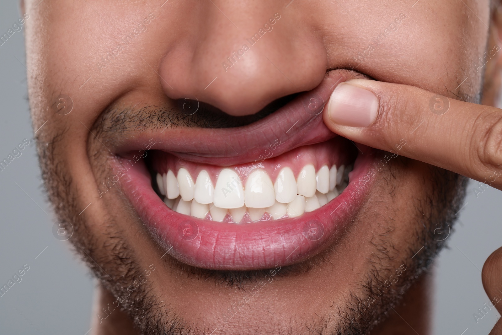 Photo of Man showing healthy gums on grey background, closeup