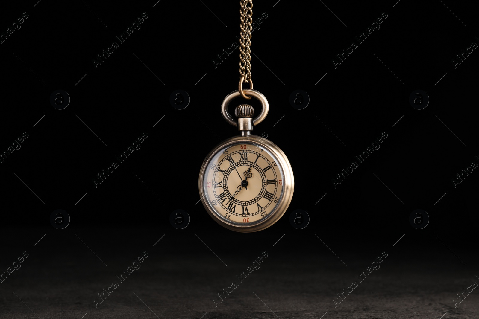 Photo of Stylish pendulum above table on black background. Hypnotherapy session