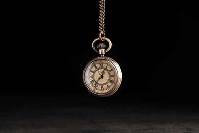 Stylish pendulum above table on black background. Hypnotherapy session