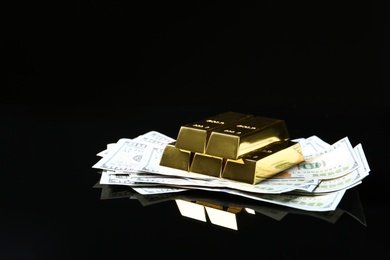 Photo of Shiny gold bars and money on black background