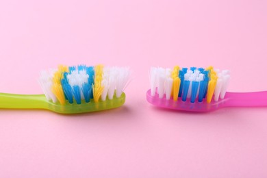 Photo of Colorful plastic toothbrushes on pink background, closeup