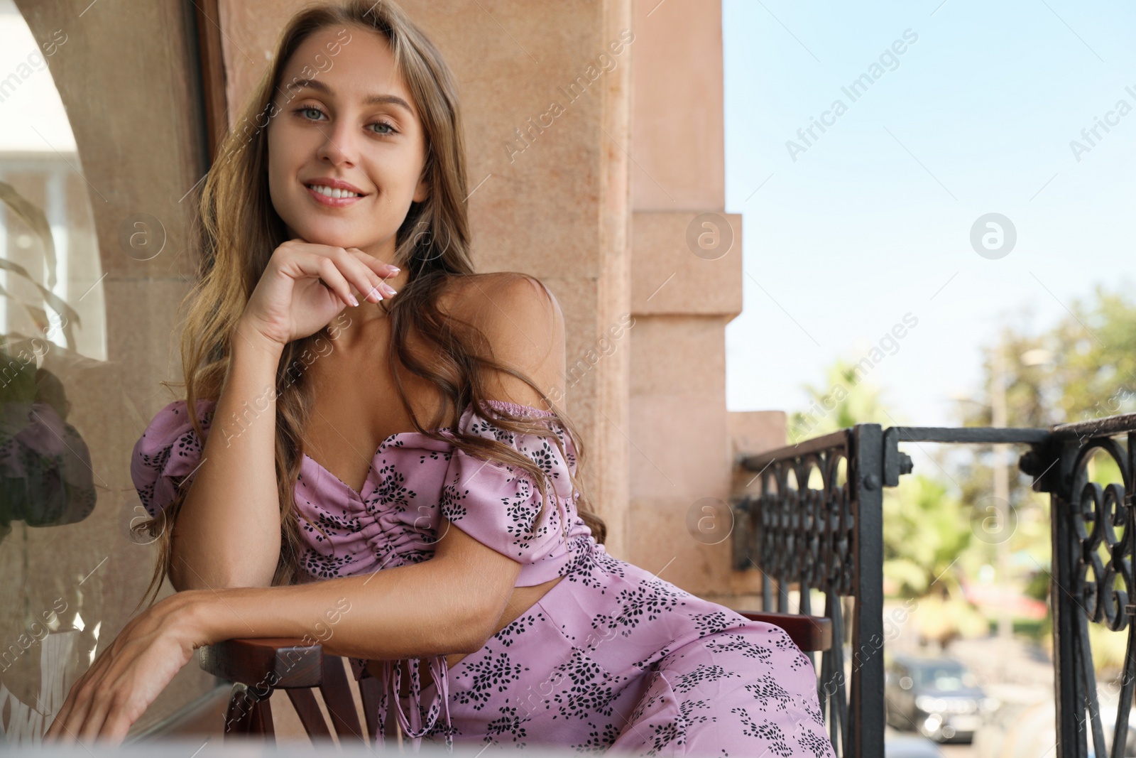 Photo of Beautiful young woman sitting on balcony, space for text