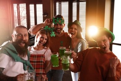 Photo of Group of friends with glasses of green beer in pub. St. Patrick's Day celebration
