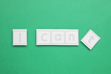 Photo of Motivation concept. Changing phrase from I Can't into I Can by removing paper with letter T on green background, top view
