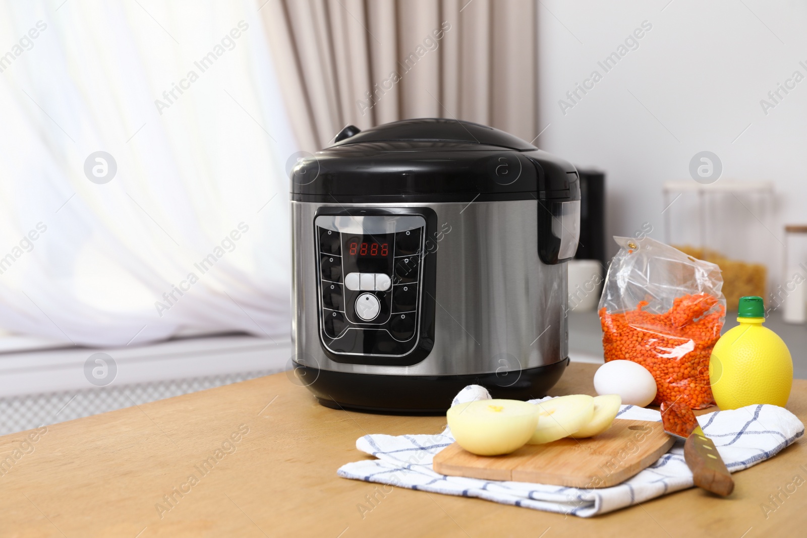 Photo of New modern multi cooker and products on table in kitchen