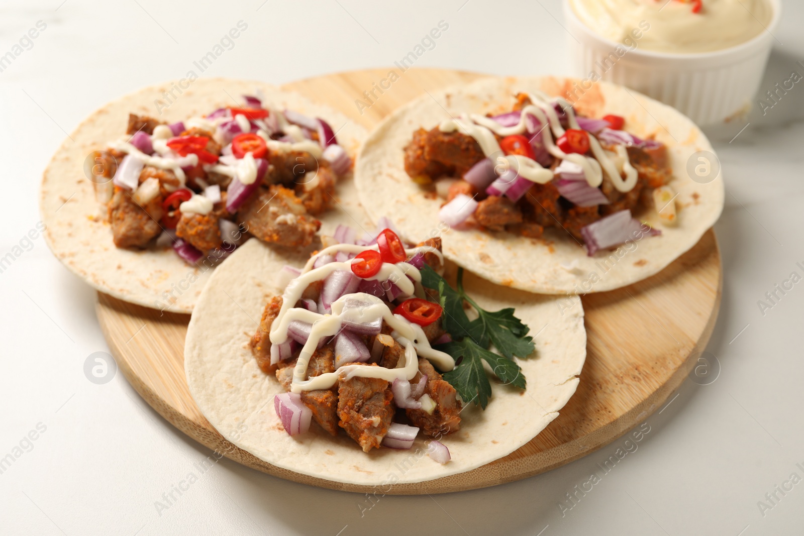 Photo of Delicious tacos with vegetables, meat and sauce on white table