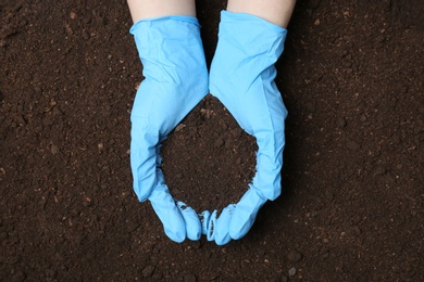 Photo of Scientist holding pile of soil above ground, top view