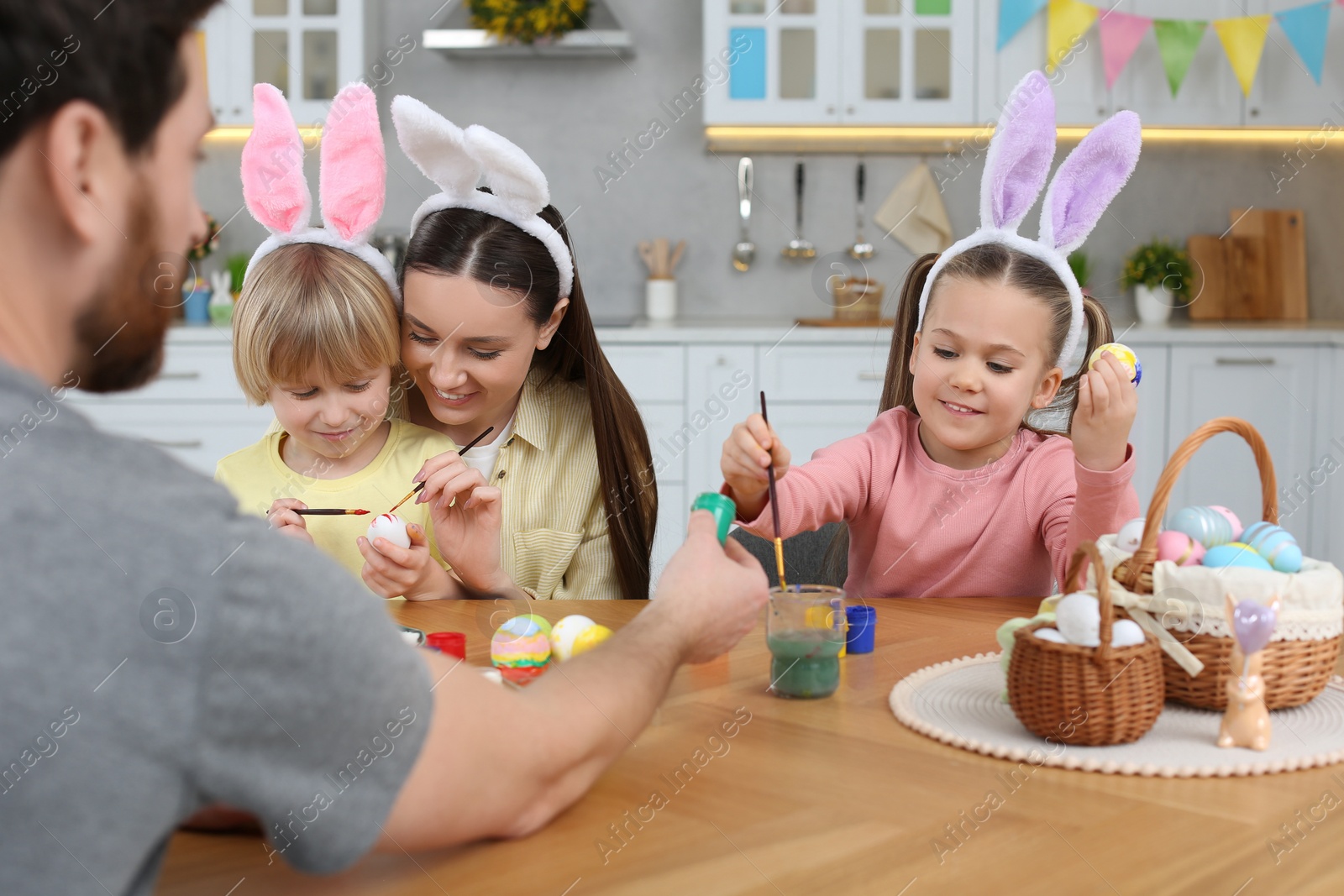 Photo of Happy family painting Easter eggs at table in kitchen