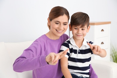 Photo of Hearing impaired mother and her child talking with help of sign language indoors