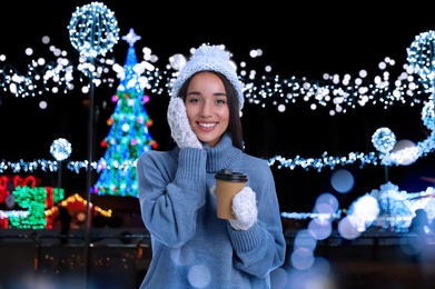 Image of Happy beautiful woman with paper cup of mulled wine at Christmas fair