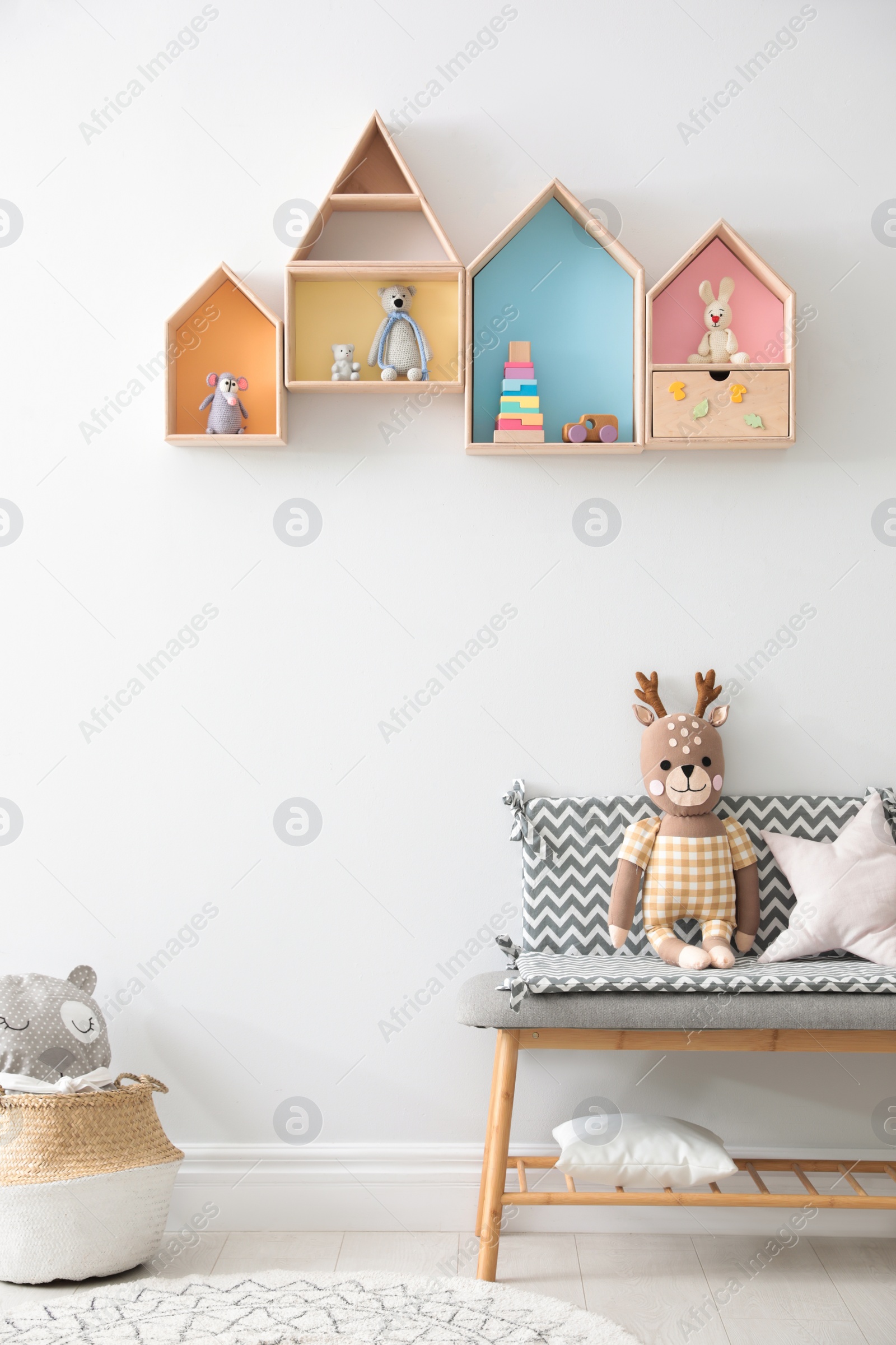 Photo of House shaped shelves and bench with toys in children's room. Interior design