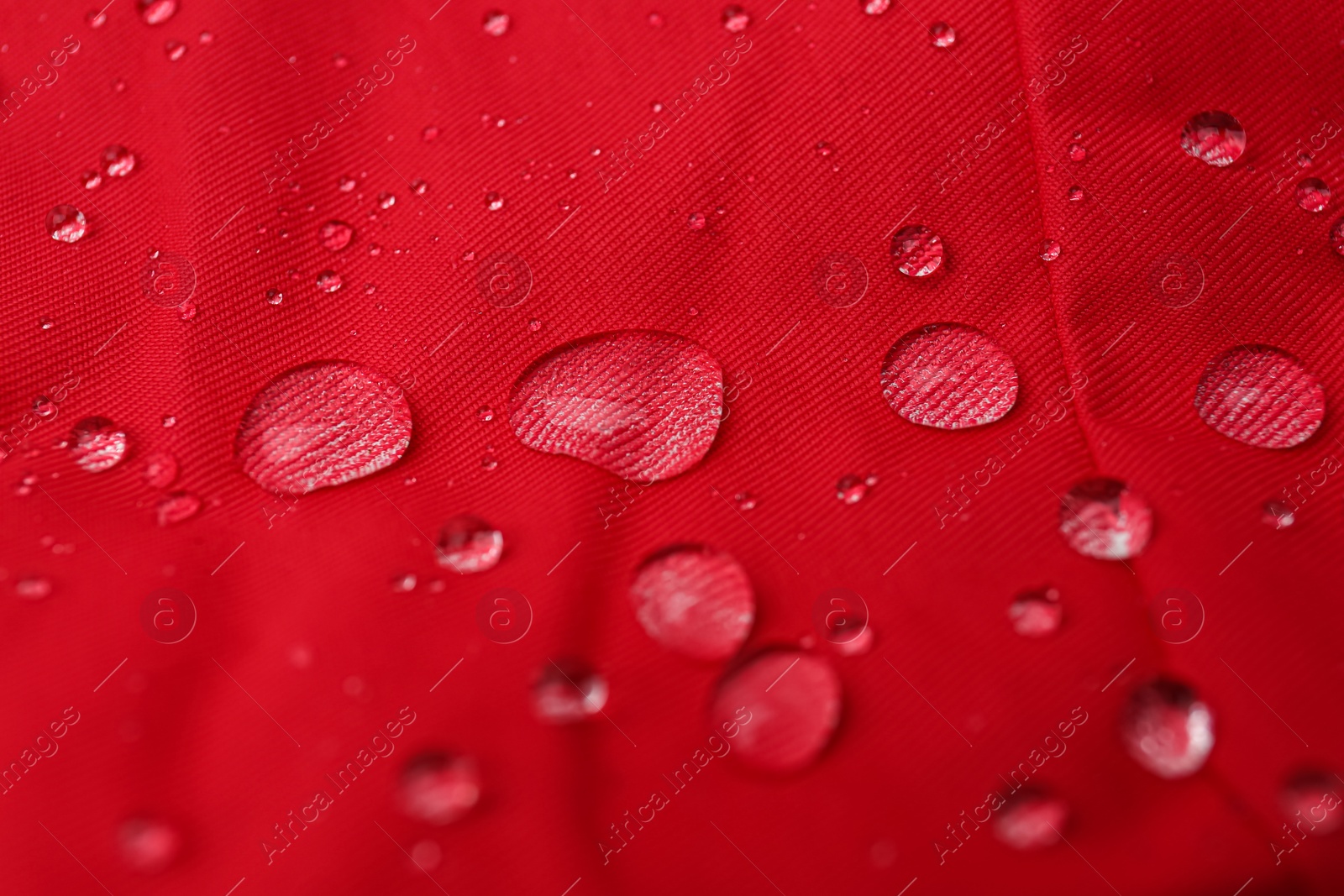 Photo of Red waterproof fabric with water drops as background, closeup