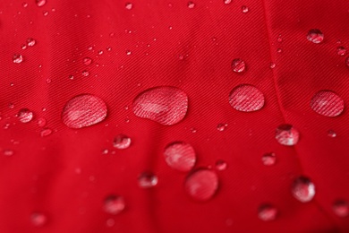 Photo of Red waterproof fabric with water drops as background, closeup