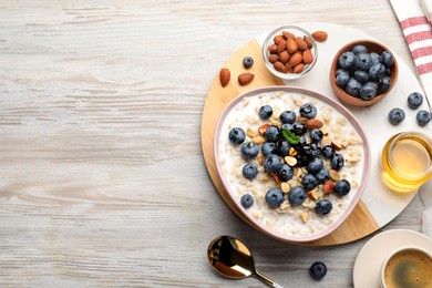 Photo of Flat lay composition with tasty oatmeal porridge and ingredients served on wooden table. Space for text