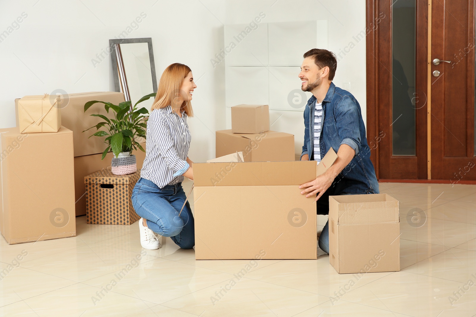 Photo of Happy couple unpacking moving box in their new house