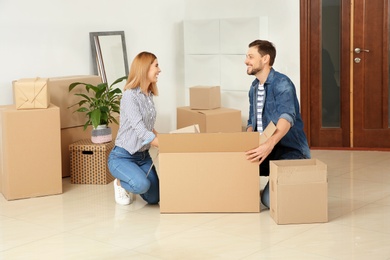 Happy couple unpacking moving box in their new house