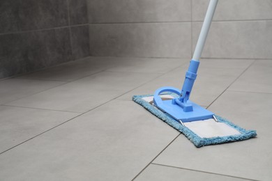 Cleaning grey tiled floor with mop, space for text