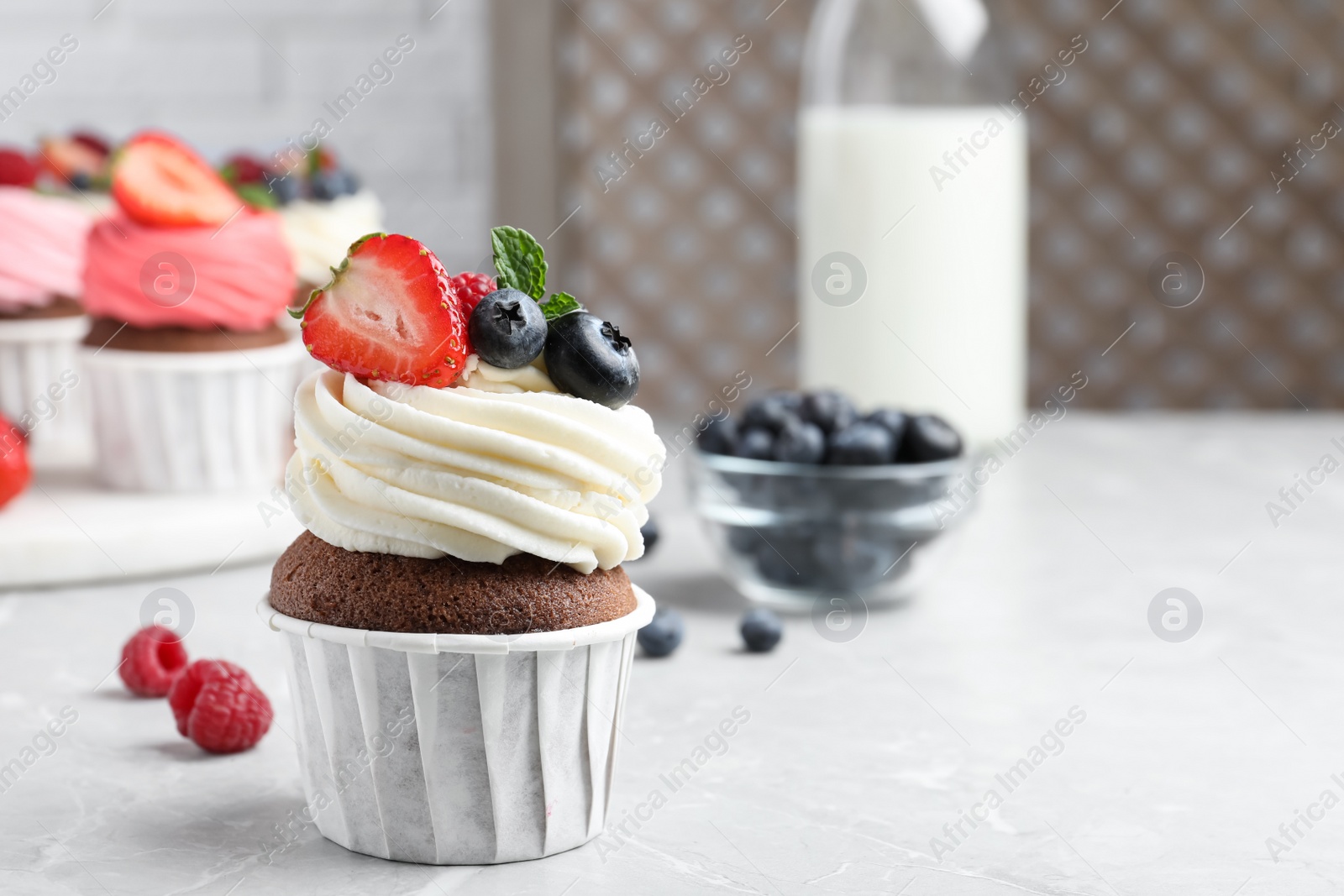 Photo of Sweet cupcake with fresh berries on light marble table. Space for text