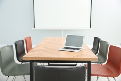 Conference room interior with laptop on wooden table