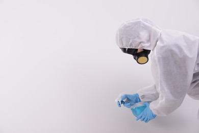 Photo of Woman in protective suit cleaning mold with sprayer on wall. Space for text