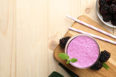 Photo of Delicious blackberry smoothie in glass and berries on wooden table, flat lay. Space for text