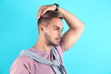 Young man with trendy hairstyle on color background