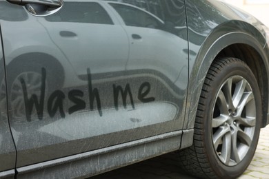 Photo of Phrase Wash Me written on dirty car, closeup