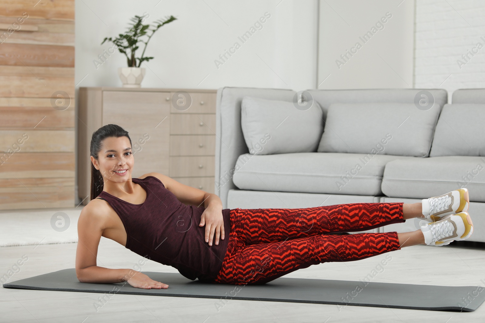 Photo of Young woman in fitness clothes doing exercise at home