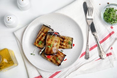 Delicious baked eggplant rolls served on white wooden table, flat lay