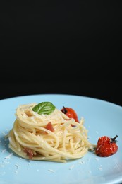 Photo of Tasty spaghetti with tomatoes and cheese on plate against black background, closeup. Exquisite presentation of pasta dish