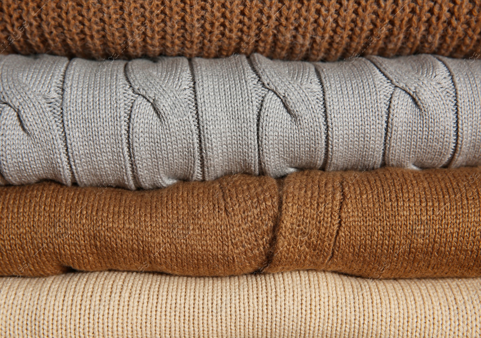 Photo of Stack of folded knitted sweaters as background, closeup
