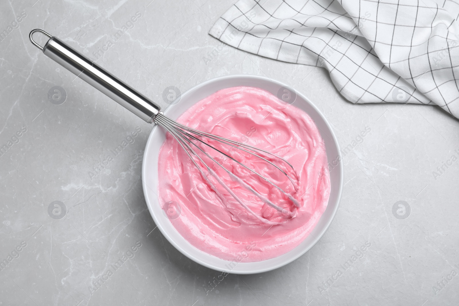 Photo of Pink cream with balloon whisk on light grey table, flat lay