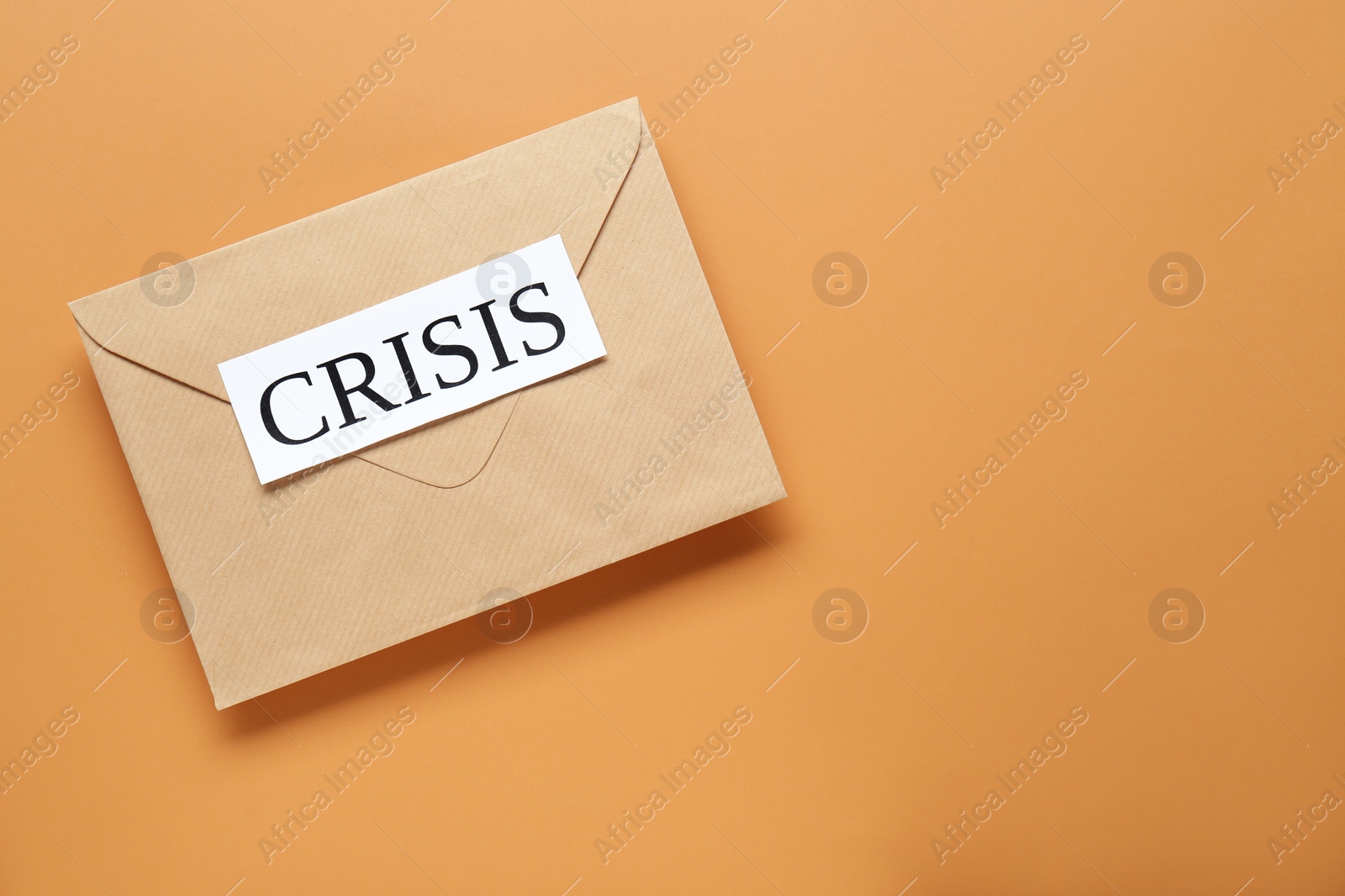 Photo of Envelope with word Crisis on brown background, top view. Space for text