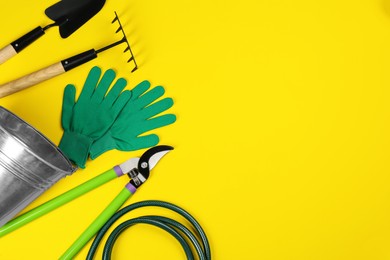 Flat lay composition with gardening tools on yellow background, space for text