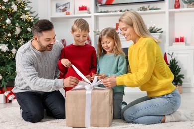 Photo of Parents and their children opening Christmas gift at home