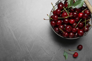 Sweet juicy cherries with leaves on grey table, flat lay. Space for text