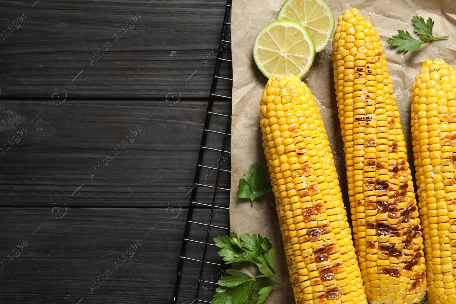 Photo of Tasty grilled corn on wooden table, flat lay. Space for text