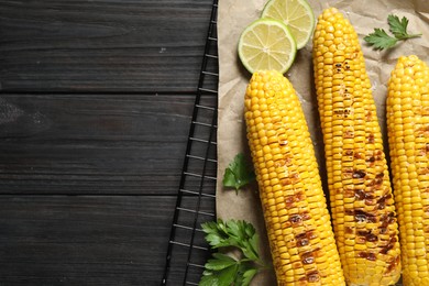 Tasty grilled corn on wooden table, flat lay. Space for text