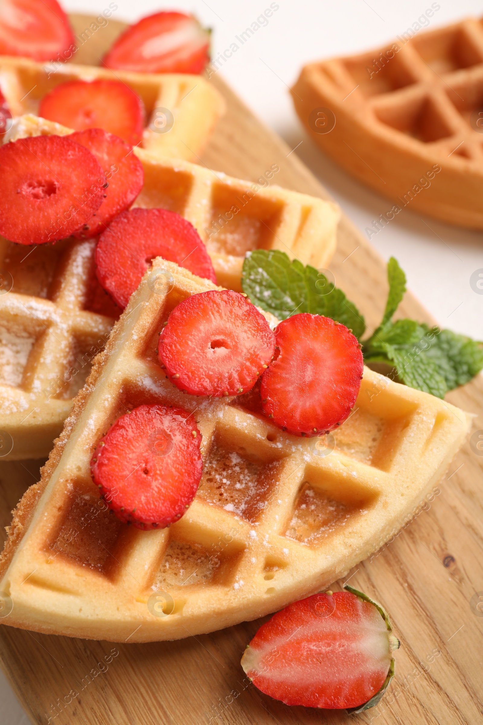 Photo of Tasty Belgian waffles with strawberries and mint on table, closeup