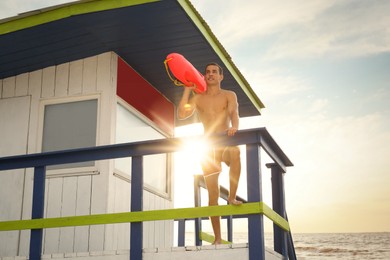 Photo of Handsome lifeguard with life buoy on watch tower