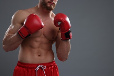 Photo of Man in boxing gloves on grey background, closeup. Space for text