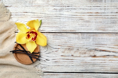 Photo of Vanilla flower and sticks on wooden background