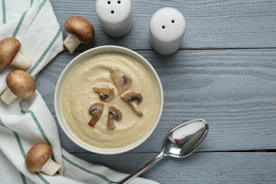 Photo of Delicious mushroom cream soup served on light grey wooden table, flat lay. Space for text